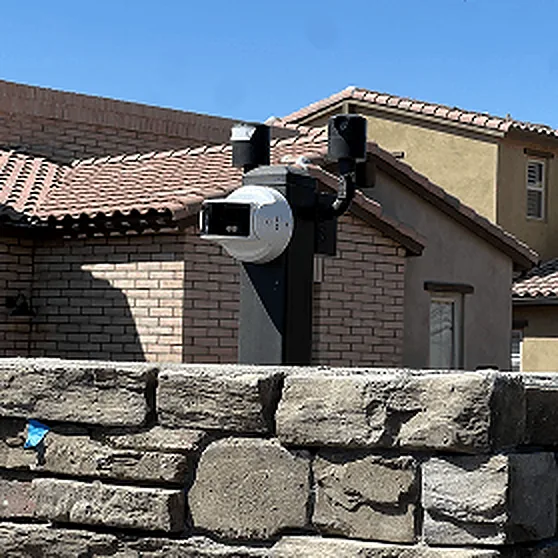 Camera and reader post above a stacked-stone wall