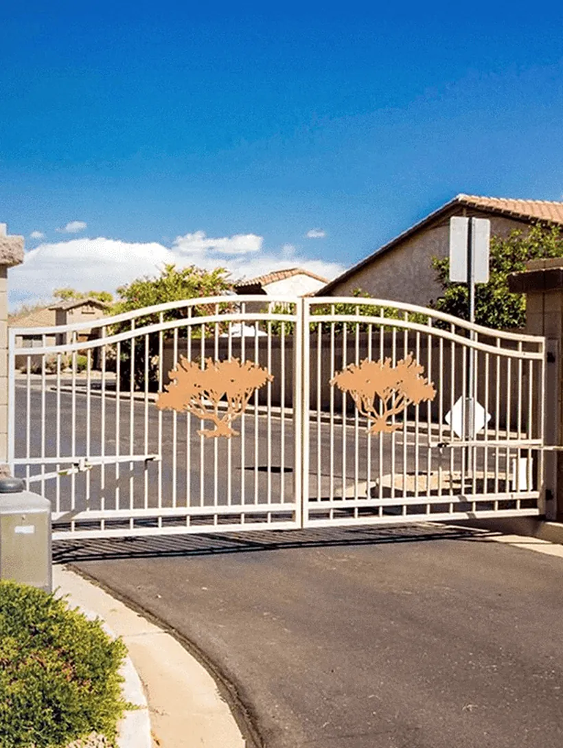 Double swing gate with tree-motif panels at a community vehicle entrance