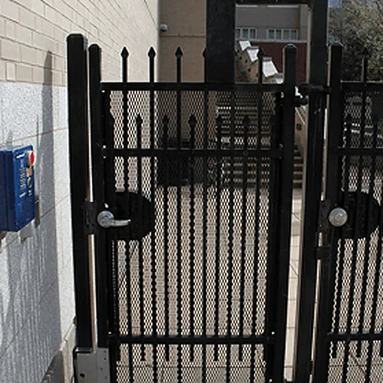 Pedestrian gate with a lever lock next to a wall-mounted blue call box