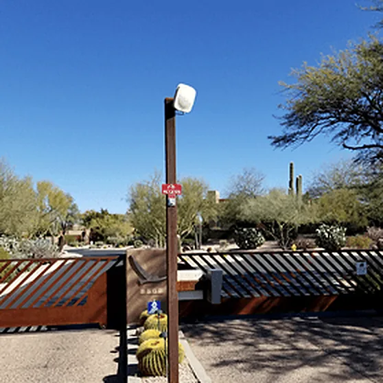 Camera on a steel post above a slatted gate in desert landscaping