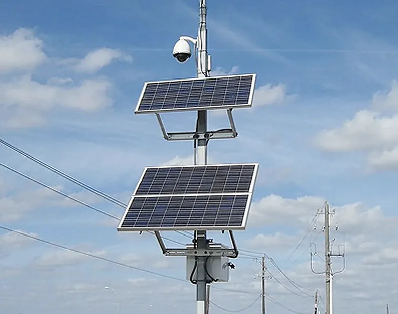 Solar-powered surveillance pole with a dome camera above two solar panels